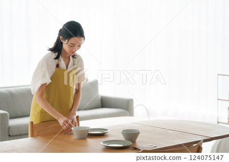 A woman in an apron putting dishes on the table 124075147