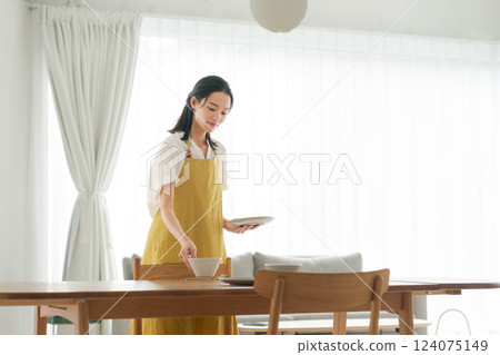 一位穿著圍裙的女人把盤子放到桌上 124075149