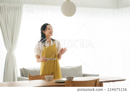 一位穿著圍裙的女人把盤子放到桌上 一位穿著圍裙的女人把盤子放到桌上 124075156