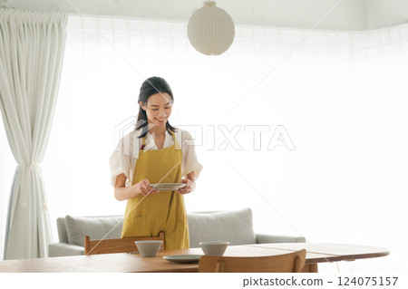 一位穿著圍裙的女人把盤子放到桌上 124075157