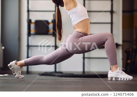 Close up view. Doing stretching. Young beautiful woman in sportive clothes have fitness day in the gym 124075406