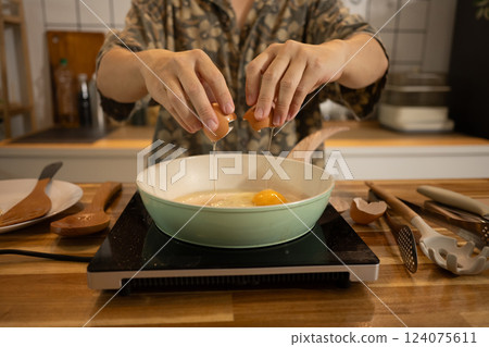 Close up shot of man cracking an egg into a frying pan, ready to prepare delicious meal 124075611