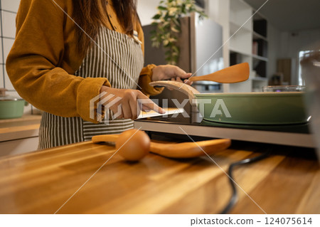 Young woman wearing striped apron preparing meal in a stylish modern kitchen 124075614