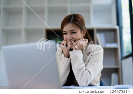 Confident business woman smiling Show successful gestures at her desk with market charts and documents in office 124075814