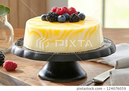 Delicious dessert cake topped with fresh berries and vibrant yellow glaze on a black cake stand Delicious dessert cake topped with fresh berries and vibrant yellow glaze on a black cake stand 124076059
