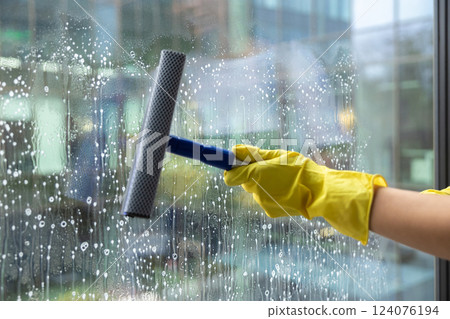 Woman in yellow gloves rubbing the window with the window washer 124076194