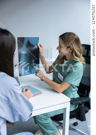 Doctor with patient looking at X-ray in office Doctor with patient looking at X-ray in office 124076287