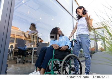 Young woman carrying a wheelchair with a disabled african american woman 124076422