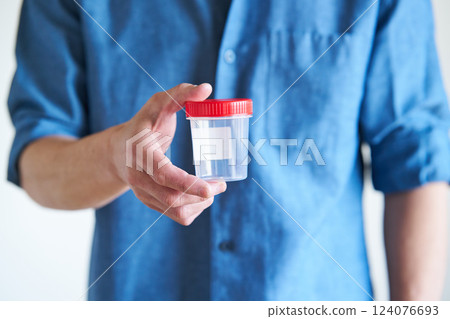 Man holding a sperm collection cup Man holding a sperm collection cup 124076693