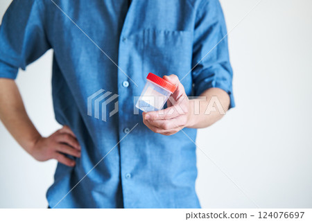 Man holding a sperm collection cup Man holding a sperm collection cup 124076697