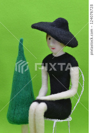 A female doll wearing a hat and sitting on a chair A female doll wearing a hat and sitting on a chair 124076728