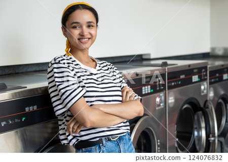 Woman in launderette using washing machine to clean her clothes Woman in launderette using washing machine to clean her clothes 124076832