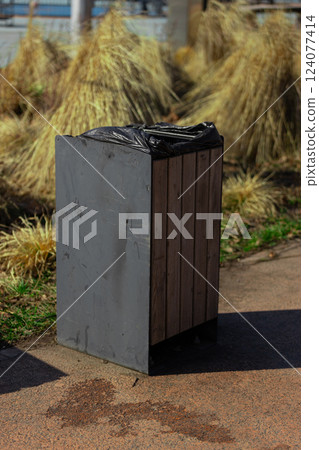 Urban Waste Management: A Sturdy Trash Bin Surrounded by Dry Grass, Presenting an Aesthetic Contrast in a Cityscape - Sustainability in Everyday Life Urban Waste Management: A Sturdy Trash Bin Surrounded by Dry Grass, Presenting an Aesthetic Contrast in a Cityscape - Sustainability in Everyday Life 124077414