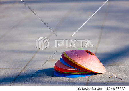Colorful Stacked Training Cones on a Paved Surface: Perfect for Sports Drills, Obstacle Courses, and Outdoor Play Activities, Inviting Fun and Fitness 124077581