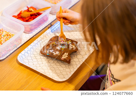Little girl making chocolate candies at the Chocolate Museum in Prague. A hands-on experience showcasing traditional chocolate-making techniques Little girl making chocolate candies at the Chocolate Museum in Prague. A hands-on experience showcasing traditional chocolate-making techniques 124077660