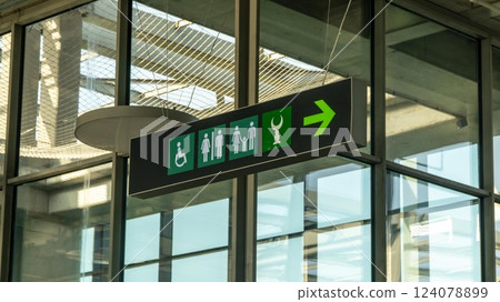 A directional sign in an airport with a showing the direction of toilets for man, woman and disabled people as well as a Islam prayer room 124078899