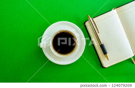 Desktop. Notepad, pen and coffee cup on green background, top view. Desktop. Notepad, pen and coffee cup on green background, top view. 124079209