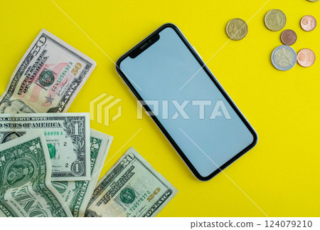 Mockup, smartphone, dollars and euro coins on a yellow background. Mockup, smartphone, dollars and euro coins on a yellow background. 124079210