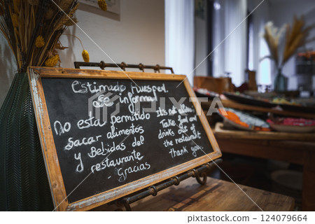 Chalkboard sign in Spanish and English inside a luxury hotel. Elegant decor features dried flowers and a buffet table, reflecting Marrakech influences. 124079664