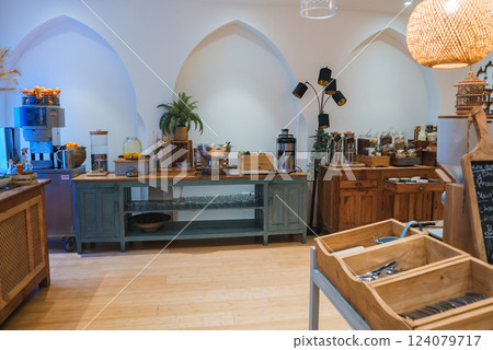 A stylish breakfast buffet area features Moroccan arched alcoves, rustic wooden furniture, and a variety of breakfast items under warm woven pendant lighting. 124079717