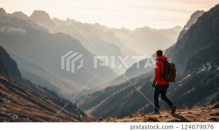 A lone hiker stands on a grassy ridge 124079976