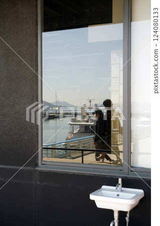 Seaside cafe terrace and two pedestrians 124080133