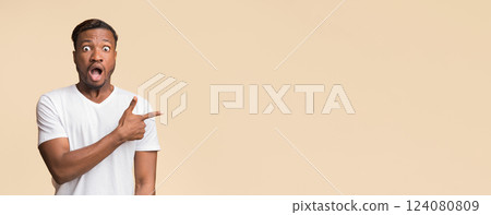 Look There. Surprised Black Man Pointing Finger Aside Standing In Studio Over Yellow Background. Free Space For Text 124080809