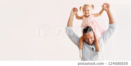 Fatherhood Concept. Little girl doing piggyback ride on her daddy's shoulders. Panorama, copy space 124080830