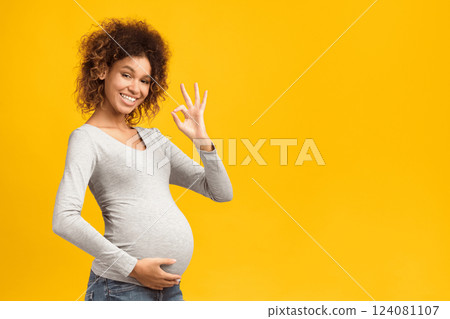 Successful pregnancy. Positive afro girl showing ok sign over pink background with empty space 124081107