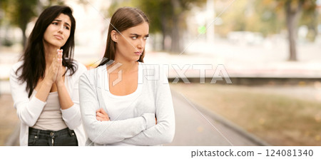 Girl Begging Offended Female Friend To Remain Friends After Quarrel Standing Outdoors. Selective Focus Girl Begging Offended Female Friend To Remain Friends After Quarrel Standing Outdoors. Selective Focus 124081340