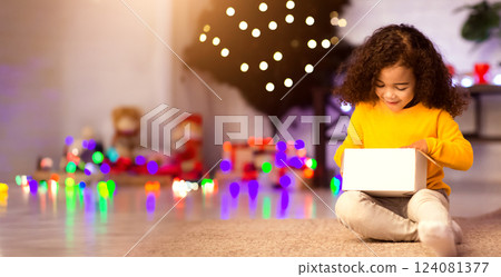 Wow. Stunned little african kid looking into Christmas gift box in amazement, free space 124081377