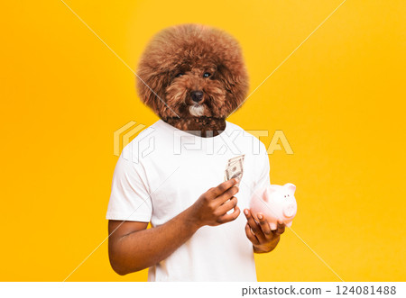 A whimsical character features a dog head on a human body, smiling while holding a banknote in one hand and a pink piggy bank in the other. The vibrant yellow background 124081488