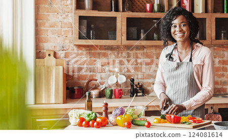 I care about my family. Beautiful black woman cooking healthy veggies salad at kitchen, smiling at camera, copy space I care about my family. Beautiful black woman cooking healthy veggies salad at kitchen, smiling at camera, copy space 124081614