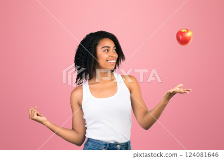 Playing With Fruits. Happy african american girl throwing red apple in the air isolated over white background, copyspace 124081646