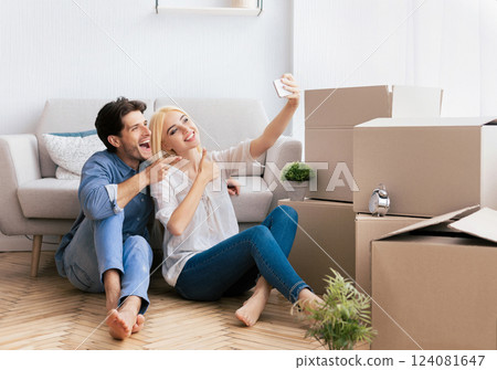 Cheerful Husband And Wife Taking Selfie Gesturing Thumbs-Up Moving Into New Apartment. House Ownership And Housewarming Concept. Free Space Cheerful Husband And Wife Taking Selfie Gesturing Thumbs-Up Moving Into New Apartment. House Ownership And Housewarming Concept. Free Space 124081647