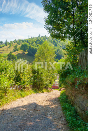 rural landscape with road in summer. countryside nature with mountain in background. rustic scenery with green grass on hill and blue sky. scenic view of gravel ground street in valley rural landscape with road in summer. countryside nature with mountain in background. rustic scenery with green grass on hill and blue sky. scenic view of gravel ground street in valley 124081756