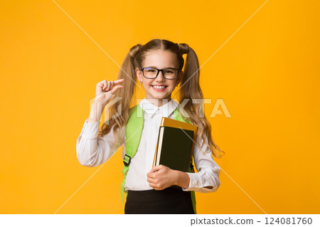 Need Some More. Nerdy School Girl Holding Books Gesturing A Little Bit Standing Over Yellow Studio Background. Copy Space Need Some More. Nerdy School Girl Holding Books Gesturing A Little Bit Standing Over Yellow Studio Background. Copy Space 124081760