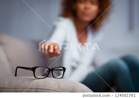 Eyesight problem. Woman reaching for eyeglasses on sofa, having poor eye sight Eyesight problem. Woman reaching for eyeglasses on sofa, having poor eye sight 124081761