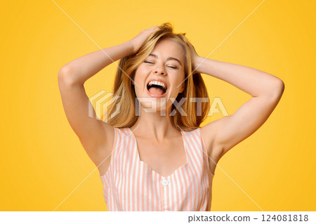 Expression Of Joy. Young girl emotionally shouting with closed eyes, standing over yellow background in studio, copy space 124081818