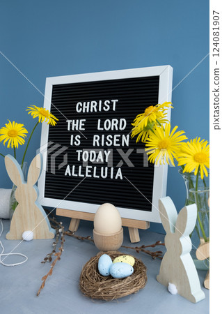 CHRIST THE LORD IS RISEN TODAY ALLELUIA text on letter board with bunny wooden figures eggs and fresh flowers. Easter composition content still life. Christian symbols of spring CHRIST THE LORD IS RISEN TODAY ALLELUIA text on letter board with bunny wooden figures eggs and fresh flowers. Easter composition content still life. Christian symbols of spring 124081907