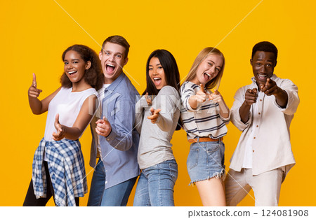 Hey there. Cheerful group of international students indicating at camera over yellow background, pointing with fingers 124081908