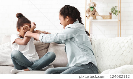 Two teenaged african girls fighting at living room, sisterhood conflict, copy space Two teenaged african girls fighting at living room, sisterhood conflict, copy space 124082112