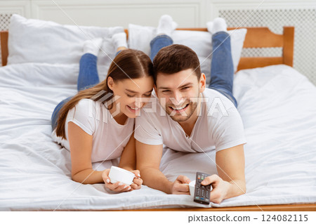Cheerful Spouses Watching TV Switching Channels Relaxing Together In Bed At Home On Weekend. Selective Focus Cheerful Spouses Watching TV Switching Channels Relaxing Together In Bed At Home On Weekend. Selective Focus 124082115