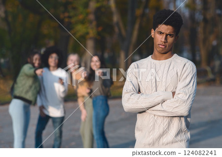 Upset african guy standing over laughing group of international teenagers, bullying concept 124082241