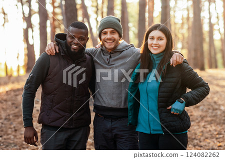 Happy adventurous international friends posing over blue tent in the middle of forest Happy adventurous international friends posing over blue tent in the middle of forest 124082262