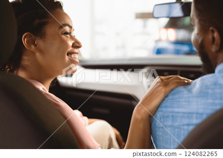 Auto Owners. Afro Wife Touching Husband's Shoulder Happy About Buying New Car In Dealership Center. Selective Focus 124082265