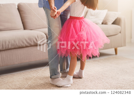 Little princess daughter standing on father feet, looking up and dancing, fatherhood, parenthood concept Little princess daughter standing on father feet, looking up and dancing, fatherhood, parenthood concept 124082348