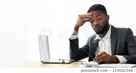 Focused african american employee taking notes in notebook at workplace in office, copy space Focused african american employee taking notes in notebook at workplace in office, copy space 124082388