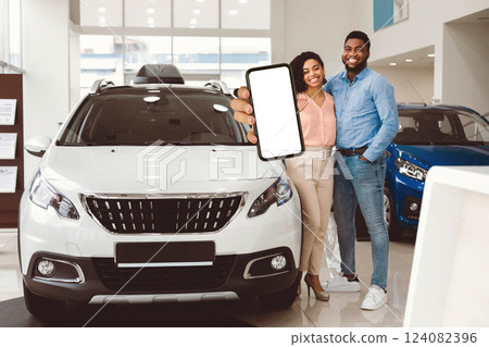 New Family Car. Cheerful Husband And Wife Holding New Automobile Key Smiling To Camera Standing Near Auto In Dealership Shop. 124082396