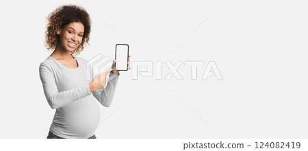 African-american pregnant woman showing cellphone with empty display, application for expectant ladie African-american pregnant woman showing cellphone with empty display, application for expectant ladie 124082419